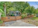 A quaint home with a picket fence and inviting gated driveway, nestled under mature trees, offering privacy at 4546 Holly St, North Charleston, SC 29405