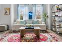 Well-lit living room boasts a cozy sofa, colorful rug, and large windows with light blue curtains at 4557 Mixson Ave, North Charleston, SC 29405