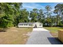 Aerial view of a light green, single-story home with a gravel and concrete driveway nestled among tall trees at 5774 Scott White Rd, Hollywood, SC 29449