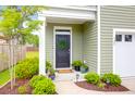 Inviting entryway with a black door adorned with a green wreath and beautiful landscaping at 725 Pepperbush St, Charleston, SC 29414