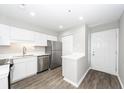 Bright kitchen features stainless steel appliances, white cabinets, and sleek countertops with a view to the entry door at 142 Marsh View Villas, Folly Beach, SC 29439