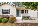 Charming single-story home with light siding, blue door, front porch and manicured landscaping at 209 Lipman St, Summerville, SC 29483