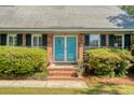 Close-up of brick entryway featuring charming blue double doors with black shutters and manicured shrubs at 968 Cummings Cir, Mount Pleasant, SC 29464