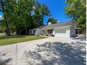 Side view of a charming white home with a garage, set on a well-manicured lawn and concrete driveway at 1534 Kentwood Cir, Charleston, SC 29412