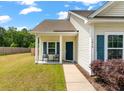 Inviting home exterior with a cozy front porch, complemented by blue shutters and well-maintained lawn at 1610 Fishbone Dr, Johns Island, SC 29455