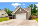 Home's front facade featuring a two-car garage, brick accents, and manicured landscaping under a blue sky at 1610 Fishbone Dr, Johns Island, SC 29455