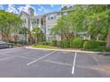 Exterior building view with mature landscaping, multiple trees, and ample parking on a partly cloudy day at 188 Midland Pkwy # 516, Summerville, SC 29485