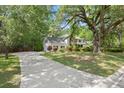 A charming two-story white house with a long driveway and well-maintained lawn surrounded by mature trees at 197 High Grove Rd, Summerville, SC 29485