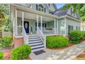 Inviting front porch with a porch swing, white railings, and a beautifully decorated entryway at 2076 Rookery Ln, Charleston, SC 29414