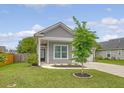 Beautifully landscaped front yard with a well-maintained lawn and a charming gray home with a covered porch at 212 Palmetto Walk Dr, Summerville, SC 29486