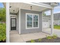 Inviting covered porch featuring stylish columns, a classic entry door, and a view of the attached two-car garage at 212 Palmetto Walk Dr, Summerville, SC 29486