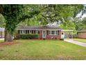 Traditional brick home showcasing a well-maintained lawn and a covered carport, exuding classic curb appeal at 2220 Pinehurst Ave, Charleston, SC 29414