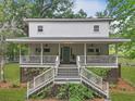 Charming two-story home with a large porch, wooden stairs, and mature landscaping at 263 Gator Walk, Ridgeville, SC 29472