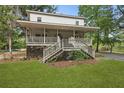 Charming two-story home with a large porch, wooden stairs, and mature landscaping at 263 Gator Walk, Ridgeville, SC 29472