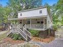 Charming two-story home with a large porch, wooden stairs, and mature landscaping at 263 Gator Walk, Ridgeville, SC 29472