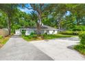 Exterior view of the single Gathering home featuring a long driveway, mature trees, and lush landscaping at 672 W Oak Forest Dr, Charleston, SC 29407