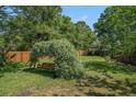 Serene backyard with a charming swing covered in flowers, surrounded by lush greenery and a wooden fence at 1250 Wide Water Ct, Charleston, SC 29412