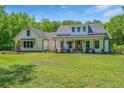 Beautiful white farmhouse with a large front yard and inviting porch perfect for relaxing at 1375 Tannanger Trl, Awendaw, SC 29429