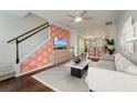 Open-concept living room with modern sofa, staircase, wood floors, and coral accent wall at 1533 Bluewater Way, Charleston, SC 29414