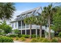 Beautiful two-story home featuring a screened porch, metal roof, and surrounded by tropical landscaping at 3305 Knot Aly, Johns Island, SC 29455