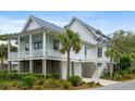 Stunning coastal home with a metal roof, inviting porch, ground level garage, and tropical landscaping at 3305 Knot Aly, Johns Island, SC 29455