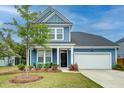 Charming blue home with a well-manicured lawn, attached garage, and covered front porch with seating at 802 S Pointe Blvd, Summerville, SC 29483