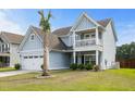 Inviting two-story home featuring a quaint porch balcony and a manicured lawn with a young palm tree at 8402 Loggers Run, North Charleston, SC 29420
