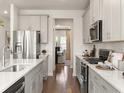 Stylish kitchen featuring stainless steel appliances, light gray cabinets, and hardwood floors leading to the dining area at 105 Indigo Cove Blvd, Summerville, SC 29486
