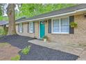 Charming brick home featuring a vibrant turquoise front door, a well-manicured yard, and a welcoming entrance at 141 Larson Dr, Summerville, SC 29485