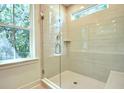 Modern walk-in shower featuring beige subway tile, a glass door, and a window at 1423 Clay Field Trl, Summerville, SC 29485