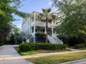 Inviting two-story home with double porches, a palm tree, and lush landscaping at 1543 Wando Landing St, Charleston, SC 29492