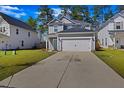Charming two-story home with gray siding, an attached garage, a well-manicured lawn, and lush, mature trees at 164 Wappoo Trace Ln, Summerville, SC 29486