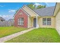 Close-up of a cozy home with light siding, a brick accent, well-manicured lawn and sidewalk at 206 Barnwell St, Summerville, SC 29483