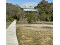 Secluded home with a metal roof surrounded by trees and marshland accessible by a wooden walkway at 211 Pelican Flight Dr # 1/6Th Share, Dewees Island, SC 29451
