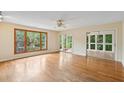 A spacious room with hardwood floors, large windows with green views, and sliding door access to a screened porch at 3109 Ion Ave, Sullivans Island, SC 29482