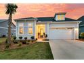 Charming home featuring a well-manicured lawn, a palm tree, and a two-car garage at sunset at 511 Ocean Mist Way, Summerville, SC 29486