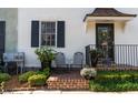 Inviting brick porch with wrought iron railing, chairs, and lush plantings near the front door at 166 1/2 Queen St, Charleston, SC 29401