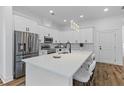 Bright kitchen featuring an island with barstool seating, pristine white cabinetry, and stainless steel appliances at 1989 Groveland Ave, North Charleston, SC 29405