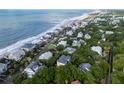 Picturesque aerial view of a coastal community with stunning homes, lush greenery, and the serene ocean stretching to the horizon at 26 Beachwood East, Isle of Palms, SC 29451