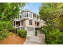 Charming three-story home showcasing double balconies, well-maintained landscaping, and convenient garage parking for modern living at 26 Beachwood East, Isle of Palms, SC 29451