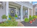 Inviting front porch with colorful potted plants, black door with wreath, and rocking chairs at 300 Saxony Loop, Summerville, SC 29486