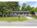 Gray brick ranch-style home with a green lawn, surrounded by mature trees at 323 Amy Dr, Goose Creek, SC 29445