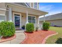 Inviting front porch with stylish columns, manicured shrubs and walkway with red mulch at 334 Cicadas Song Dr, Moncks Corner, SC 29461