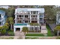 Aerial view of a multi-story home featuring a pool, balconies, well-manicured landscaping, and surrounding trees at 3803 Palm Blvd, Isle of Palms, SC 29451