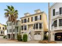 Charming yellow townhome with black shutters, white trim, stairs leading to double front doors, and a ground-level garage at 116 W 2Nd St, Folly Beach, SC 29439