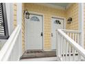 Close up of double front doors with welcome mat and outdoor lanterns, on a charming yellow townhome at 116 W 2Nd St, Folly Beach, SC 29439