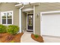 Close-up of the front entrance featuring a black door and manicured landscaping at 1173 Wading Point Blvd, Huger, SC 29450