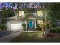 Inviting two-story home with a light gray exterior, a blue front door, and warm interior lighting at dusk at 137 Ashton Dr, Goose Creek, SC 29445