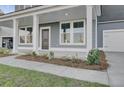Close-up of a covered front porch with white columns, a dark front door, and manicured landscaping at 199 Belfort Pl, Summerville, SC 29486
