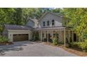 Beautiful two-story home with a covered front porch, two-car garage, and a gravel driveway surrounded by mature trees at 32 Middleton Oaks Rd, Charleston, SC 29414